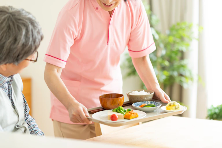 Care worker bringing lunch to a woman