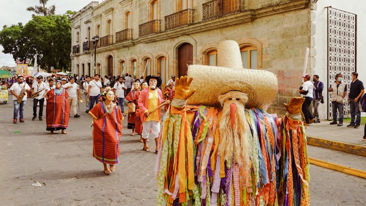 Hombre en traje de desfile tradicional con músicos.