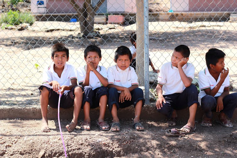 Niños con uniforme sentados en un escalón.