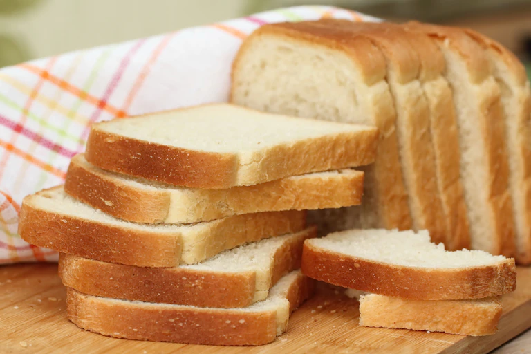Sliced supermarket bread sits on a cutting board.