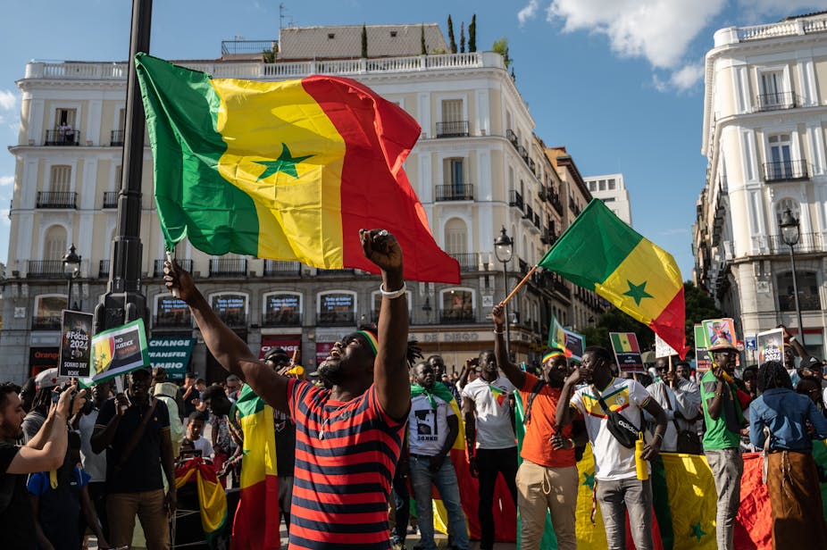 People waving Senegal flags are seen during a protest.
