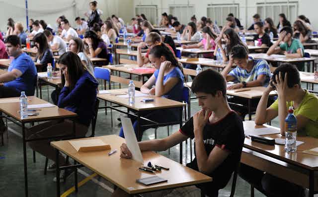 Estudiantes sentados en pupitres separados durante un examen.