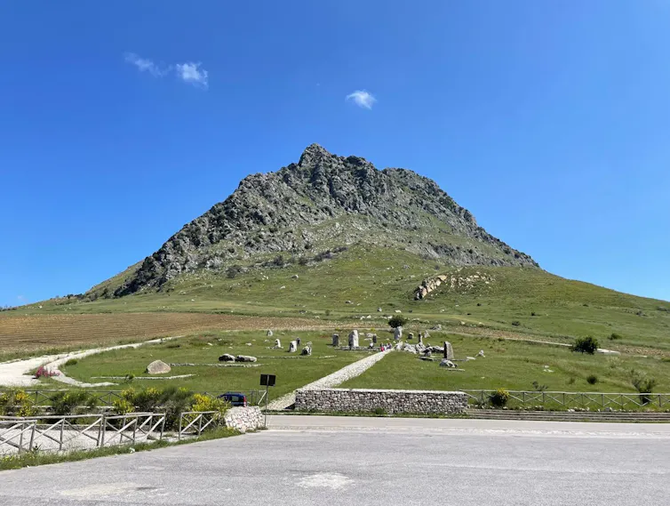 Un parque con una montaña al fondo y diferentes monolitos en una llanura.