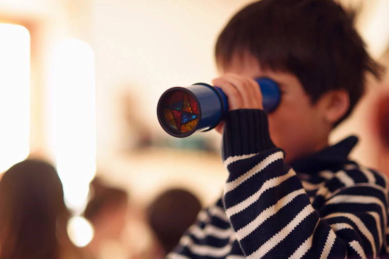 Un jeune garçon regarde à travers un kaléidoscope
