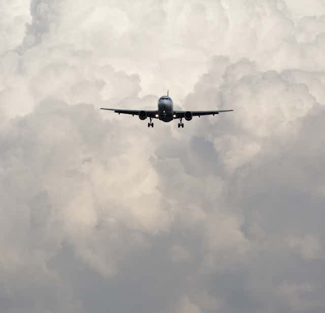 An airplane flying against the backdrop of a cloudy sky.