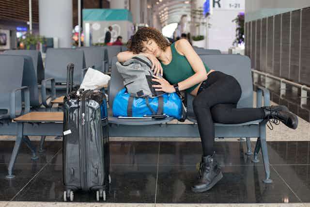 Young woman rests on luggage at airport gate