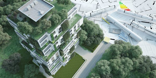 a 3D model of a green building with rolled up design plans next to it