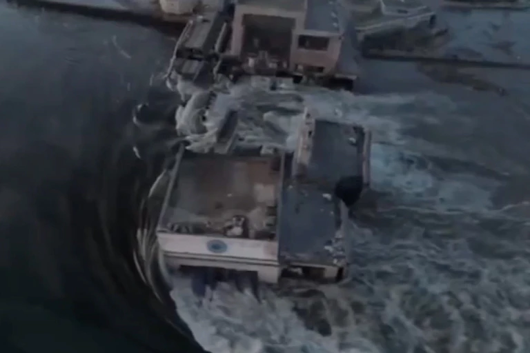 An image of water gushing over a structure that has been destroyed.