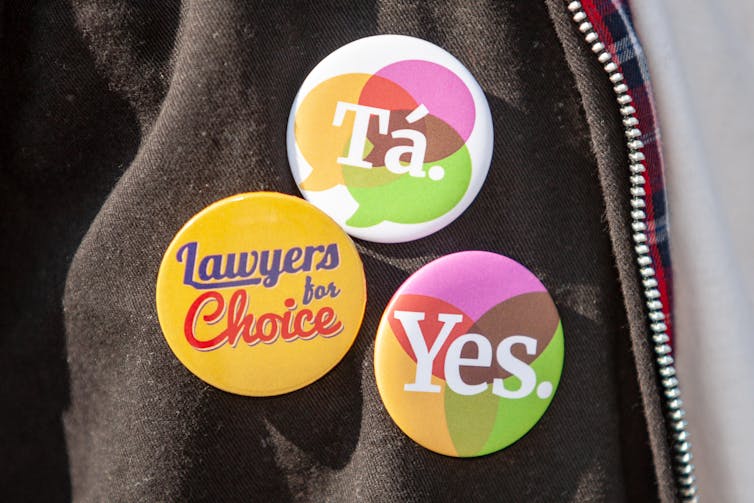 Three badges on a person's jacket, expressing support for abortion rights in Northern Ireland