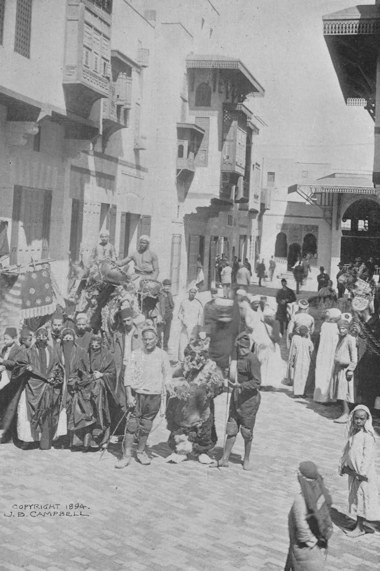 Black and white image of musicians and performers in costume posing for photographs in Cairo Street at the World's Columbian Exposition in Chicago in 1893