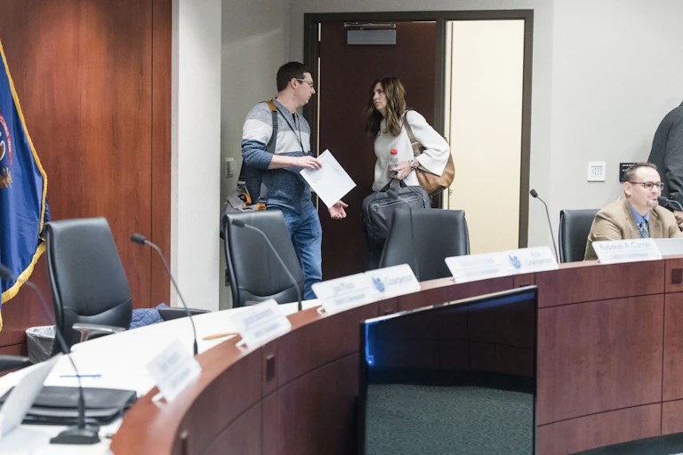 A man and a woman talking near a doorway behind a curved desk.