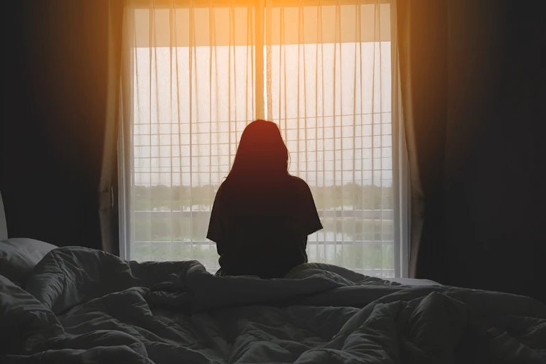 Woman sits on the edge of her bed