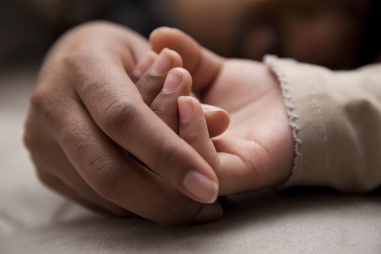 Aboriginal mother holding her child's hand