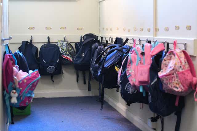 Backpacks hung up outside a classroom.