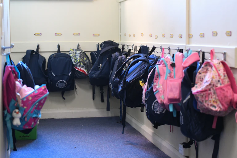 Backpacks hung up outside a classroom.