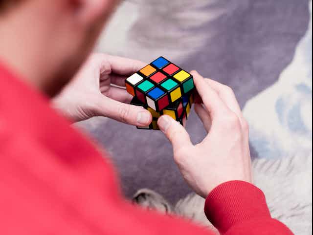 A photo of a man holding an unsolved Rubik's cube in his hands.