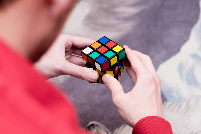 A photo of a man holding an unsolved Rubik's cube in his hands.