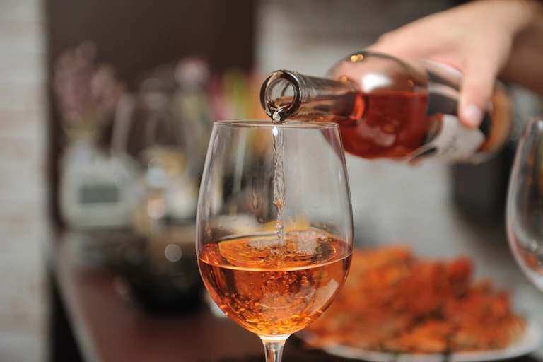 A person pouring a glass of wine from a bottle.