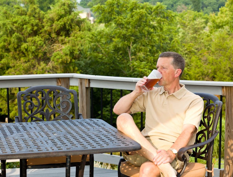 Man drinking a beer on an outdoor patio.