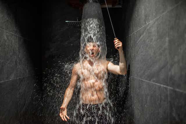 Un jeune homme prend une douche visiblement fraiche.