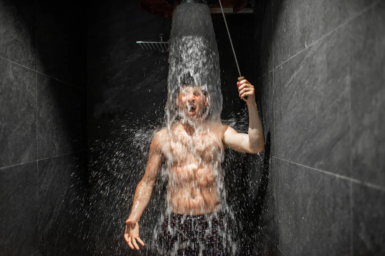 Un jeune homme prend une douche visiblement fraiche.