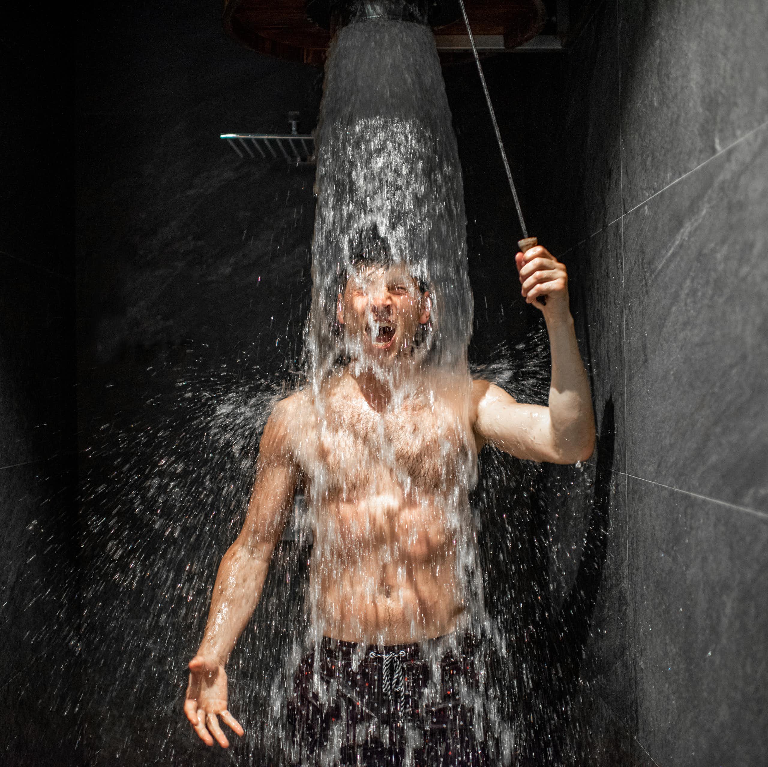 Un jeune homme prend une douche visiblement fraiche.