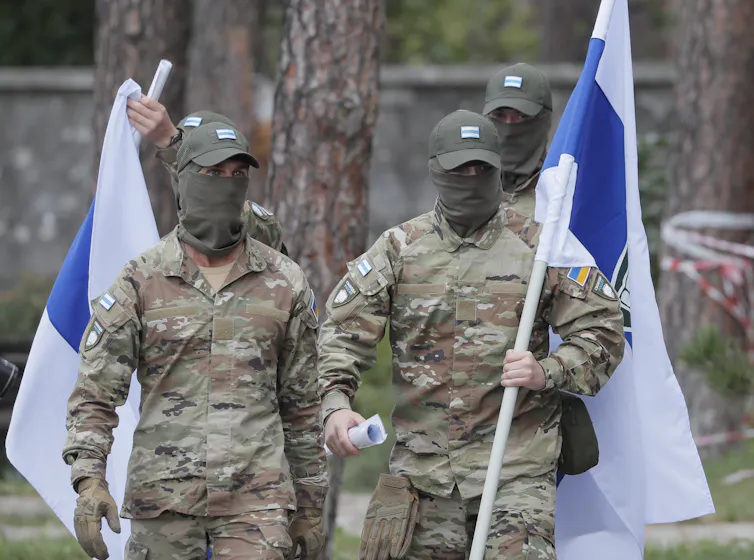 Masked fighters of the Freedom of Russia Legion with their blue, white and blue flag.