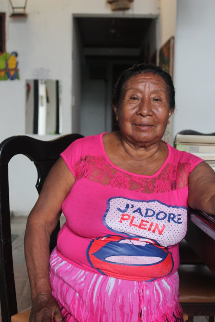 Woman in pink t-shirt sat on chair inside.