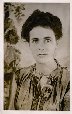 A black and white photo of Carrington wearing a moon necklace, her hair tied back.