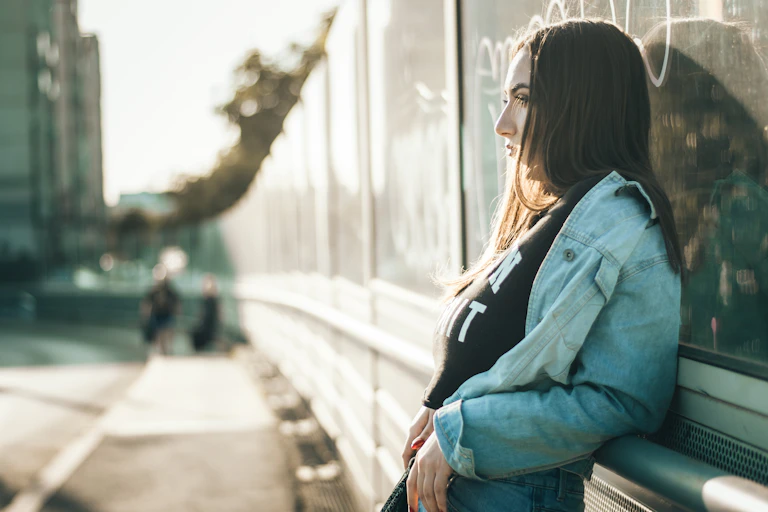 Woman leans against a public building