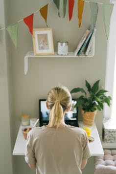 A woman sits at a desk with a laptop