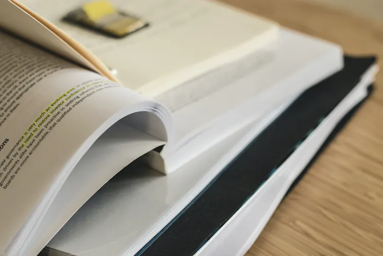 A pile of open text books, with some sticky markers