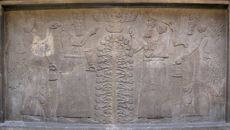 A worn stone carving of winged figures on either side of a tree.