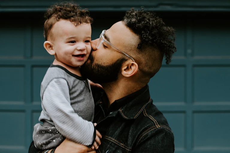 Dad kisses his happy baby's cheek