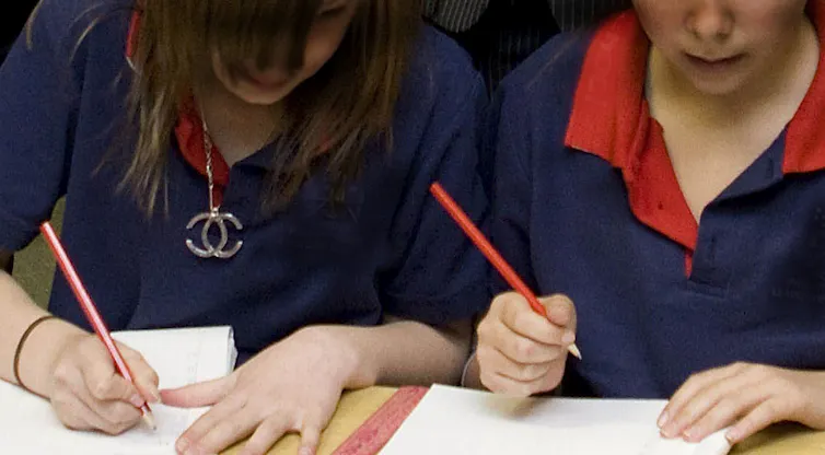Two students write on work sheets.