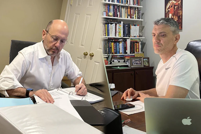 A split screen image showing a man in one room writing in a notebook, at left, while another man, at right, looks at a computer screen in a separate room.