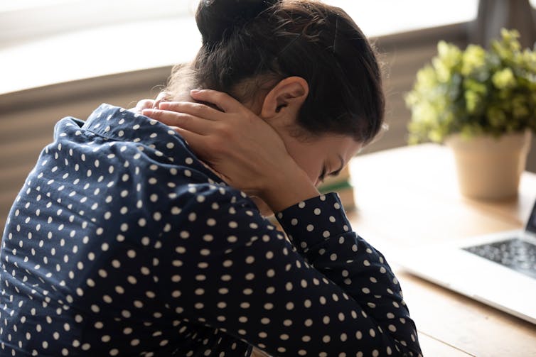 Woman holds neck in pain