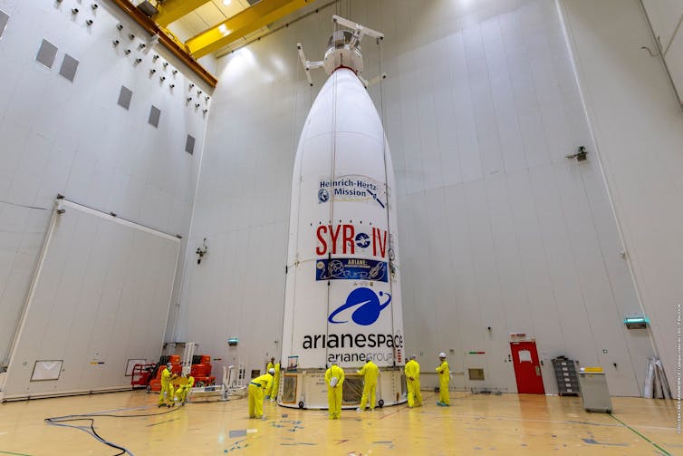 Prezent zawierający satelity w stodole z pracownikami we fluorescencyjnych ubraniach