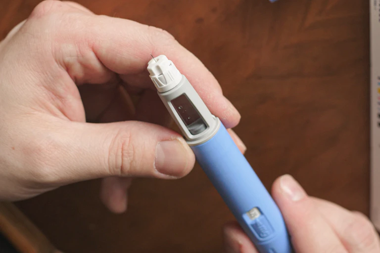 A person holding a Wegovy or Ozempic injectable.