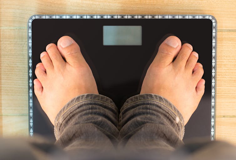 A picture of a person's feet while they stand on a bathroom scale.