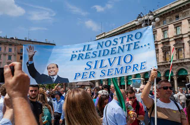 Grupo de personas sostiene una pancarta que dice: "Il nostro presidente Silvio per sempre".