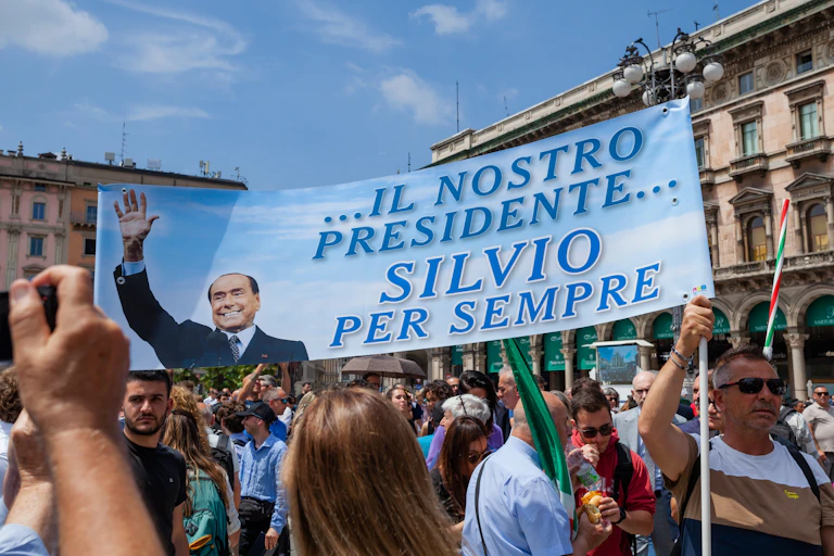 Grupo de personas sostiene una pancarta que dice: "Il nostro presidente Silvio per sempre".