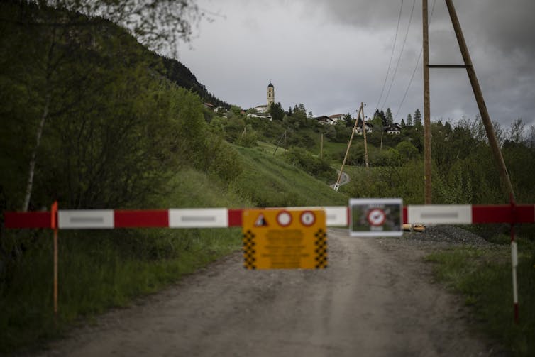 Sealed off road with warning sign, church spire in background