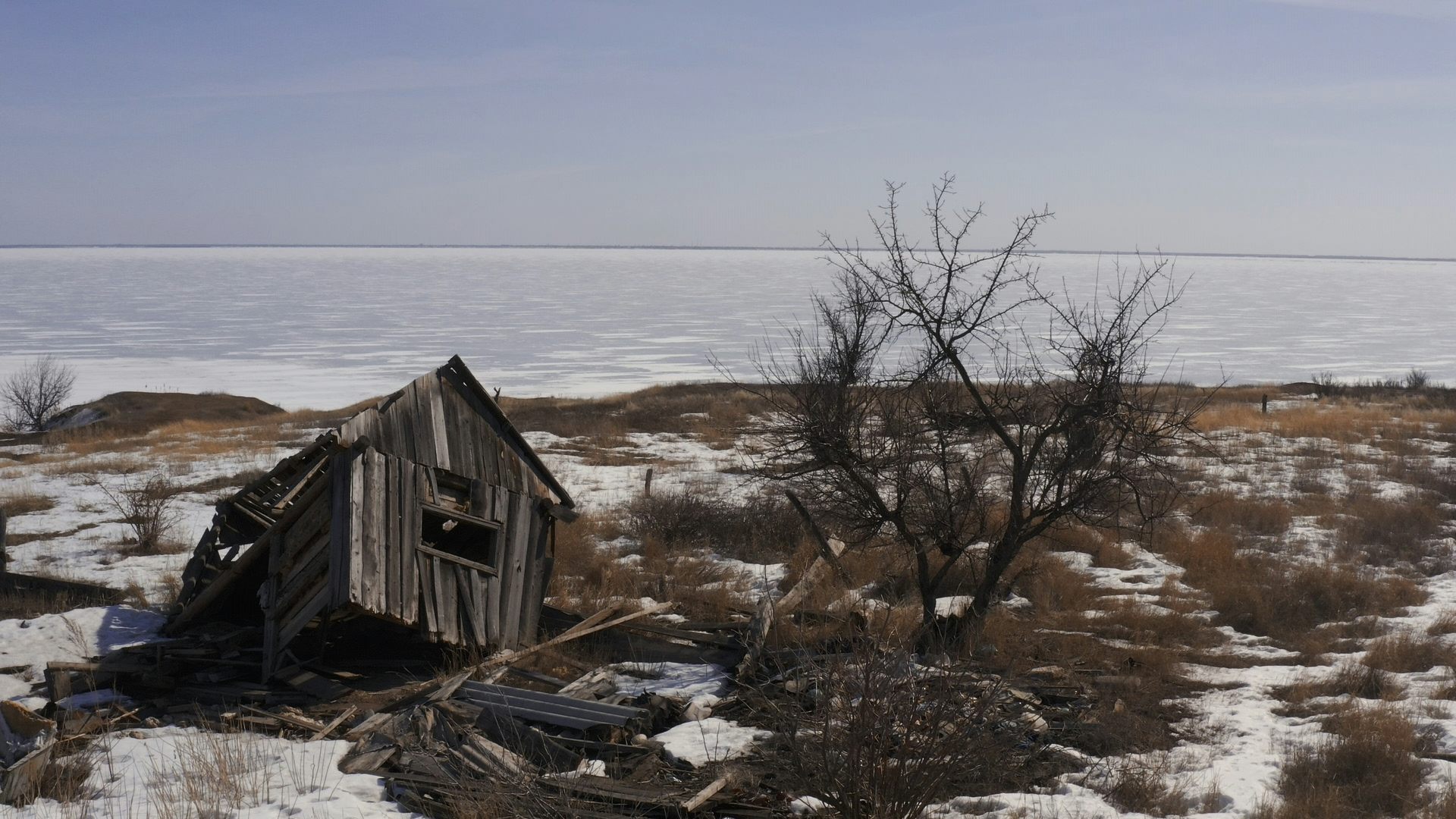 A collapsed shed-like house in a barren landscape.