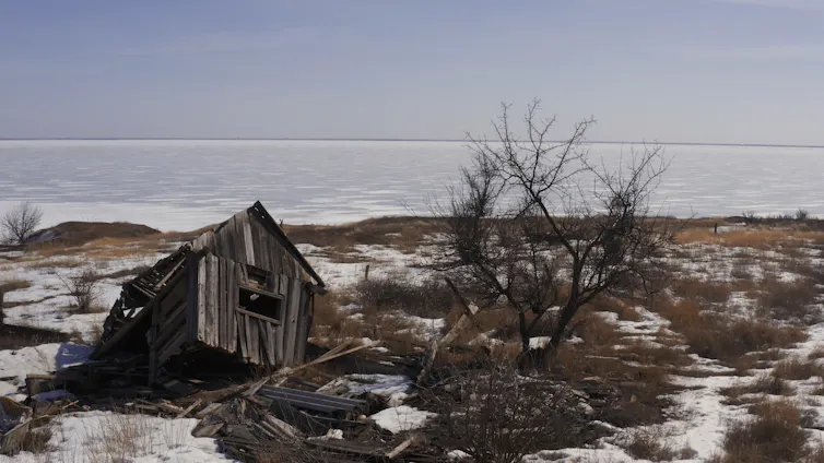 A collapsed shed-like house in a barren landscape.