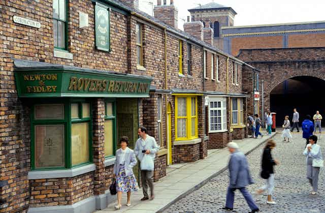 A TV set featuring a street with a railway arch and shops with pedestrians.