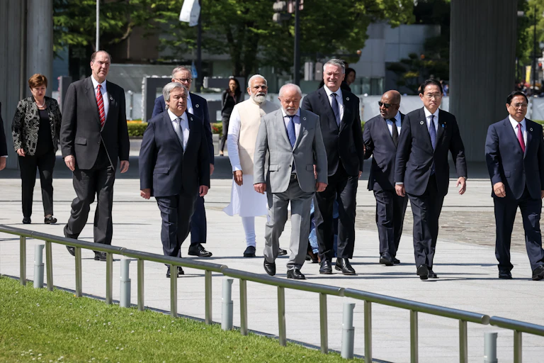 A group of men and one woman walk down a paved area.