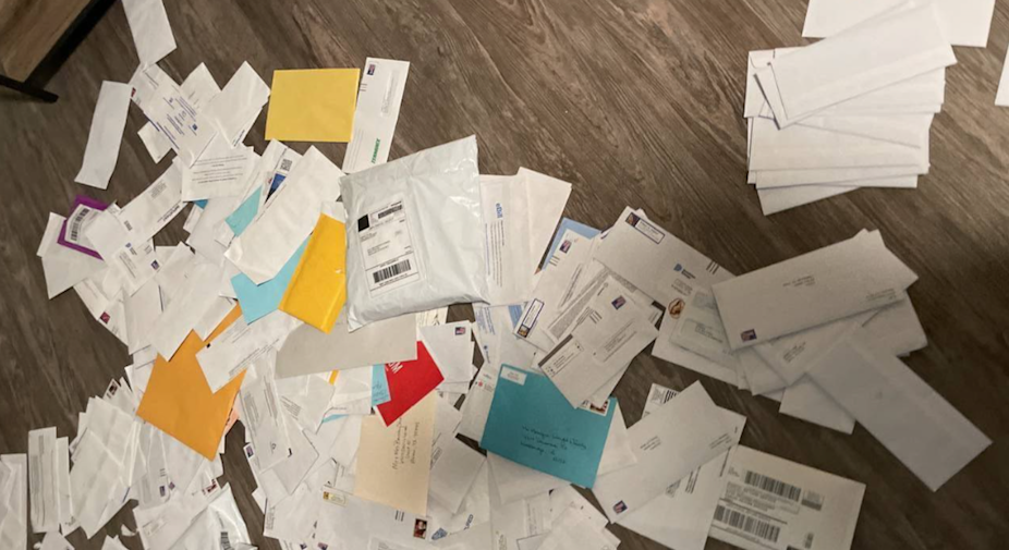 A pile of checks and other mail likely stolen from mailboxes scattered on the floor