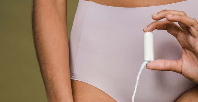 Woman in underwear holding a tampon