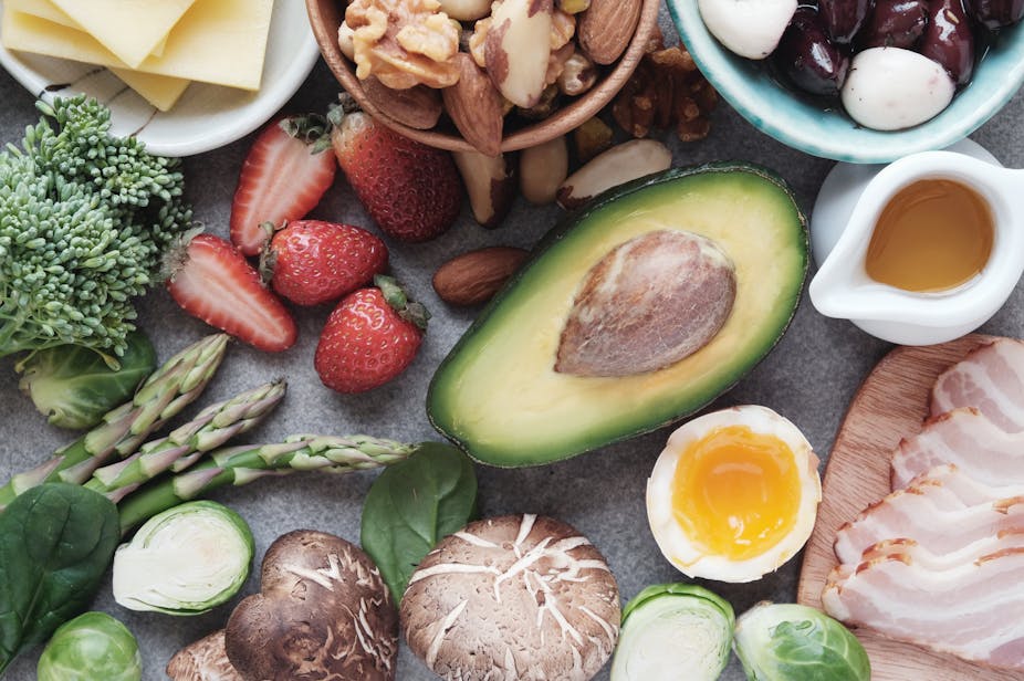 A photo of various keto-friendly foots on a table, including avocado, berries and meat.